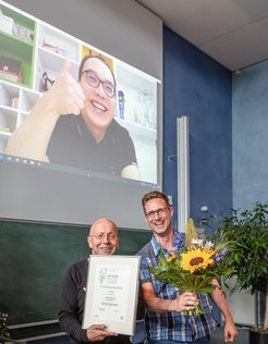Award winner Lei Yang live from China (on screen above) and Lothar Willmitzer (left) with Tobias Lortzing (right) at the award ceremony.